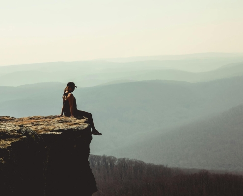 woman sitting on edge of rock formation
