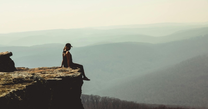 woman sitting on edge of rock formation